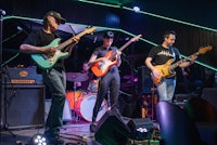 a group of people playing guitars in a bar